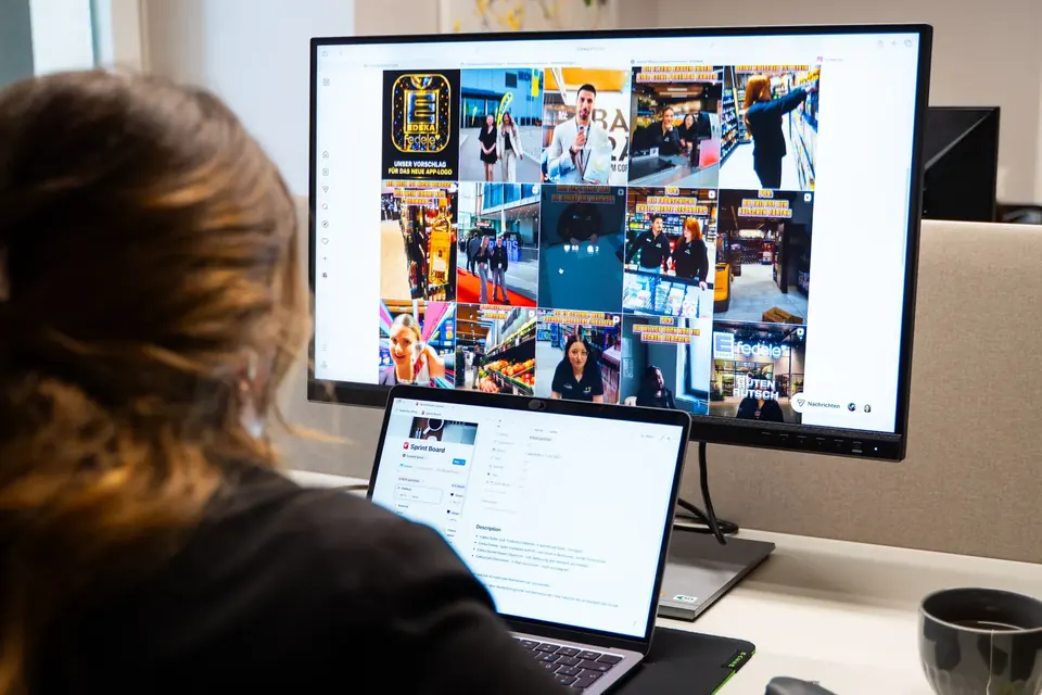 Teammitglied plant am Monitor ein Instagram-Grid im Büro