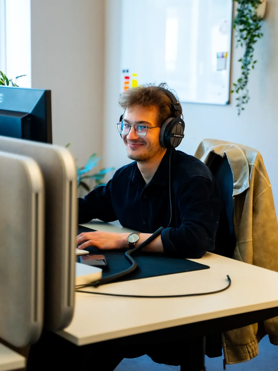 Teammitglied mit Kopfhörern arbeitet konzentriert am Monitor