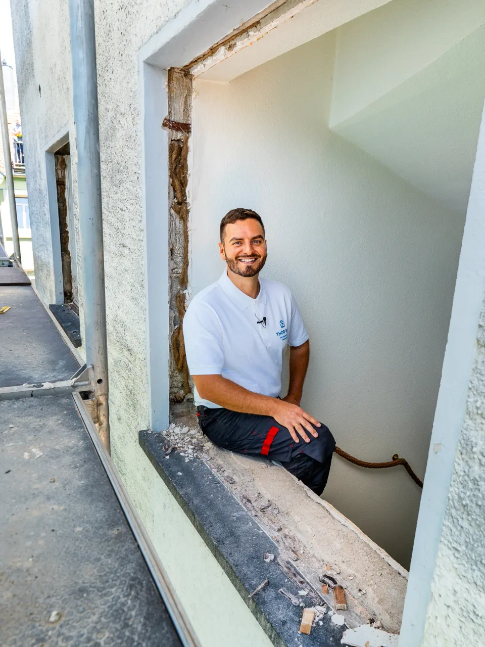 Lächelnder Handwerker mit Ansteckmikrofon beim Recruiting-Dreh auf der Baustelle