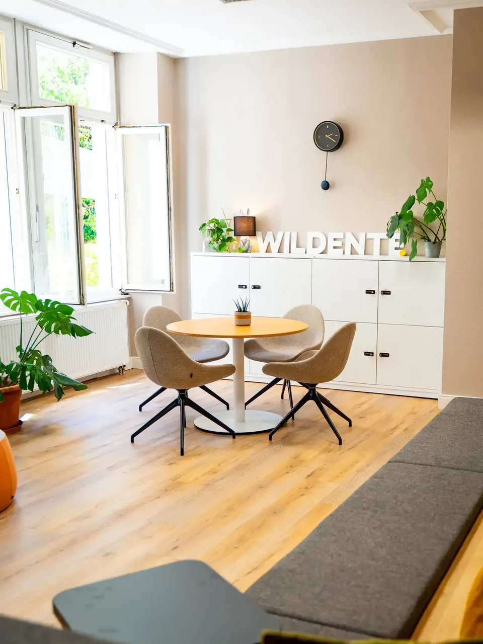 Helle Meeting-Ecke im Wildente-Büro mit rundem Tisch und Schriftzug an der Wand